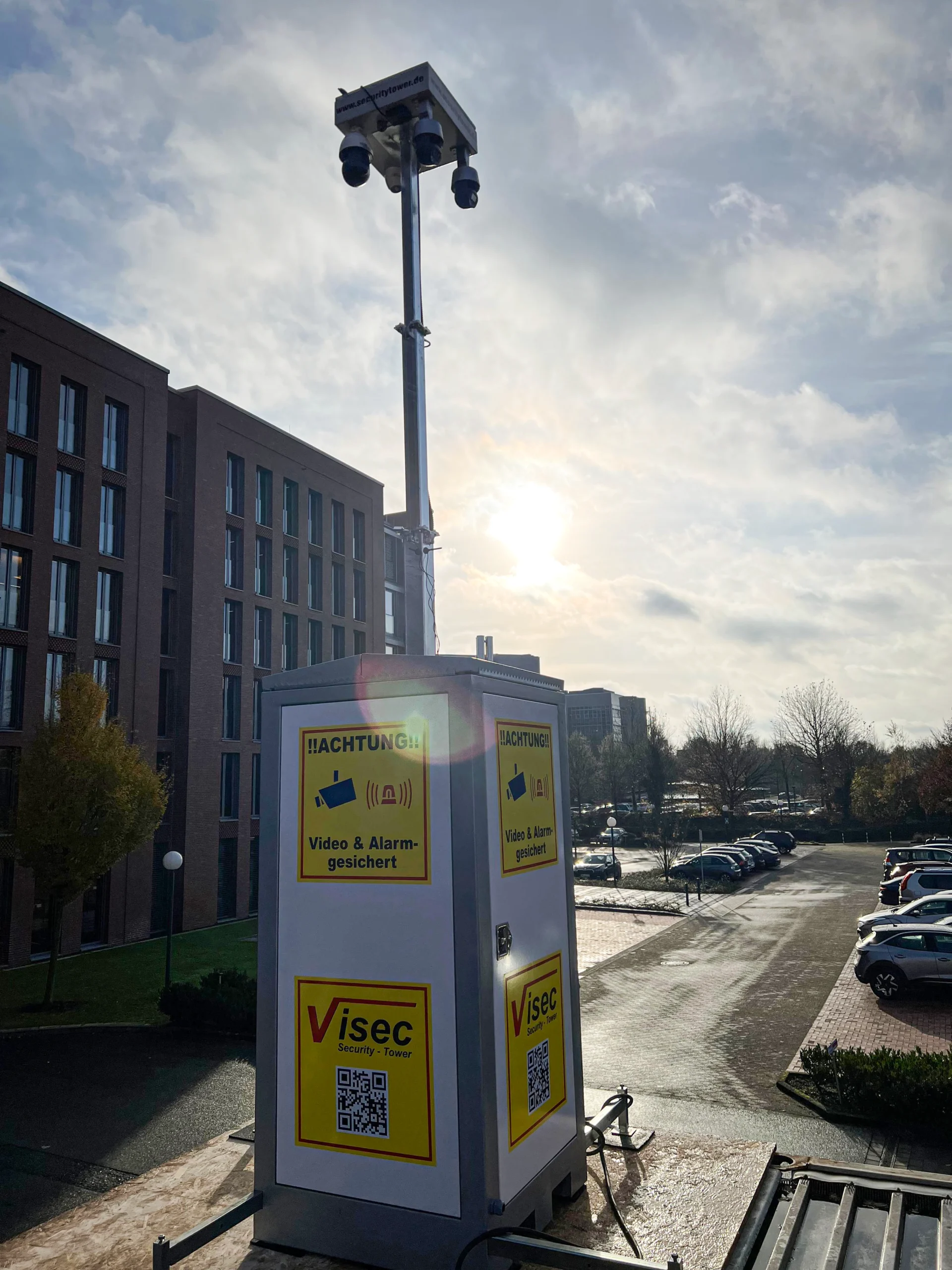 Mobiler ViSec Security Tower mit Videoüberwachung und Alarmfunktion, aufgestellt vor modernen Gebäuden.