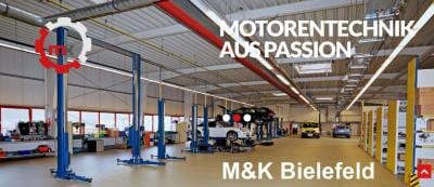 Moderne, saubere Autowerkstatt mit blauen Hebebühnen und geparkten Autos, ohne sichtbare Personen.