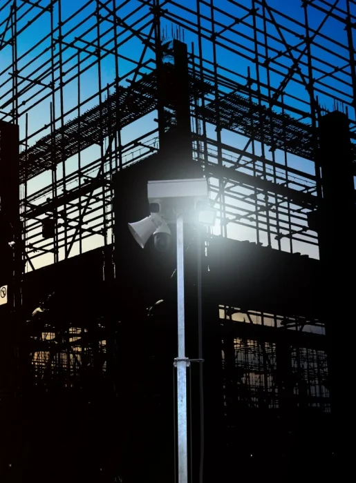 ViSec Security Tower für Baustellenüberwachung, im Vordergrund ein Turm mit Kameras und dahinter ein Gerüst bei Sonnenuntergang.