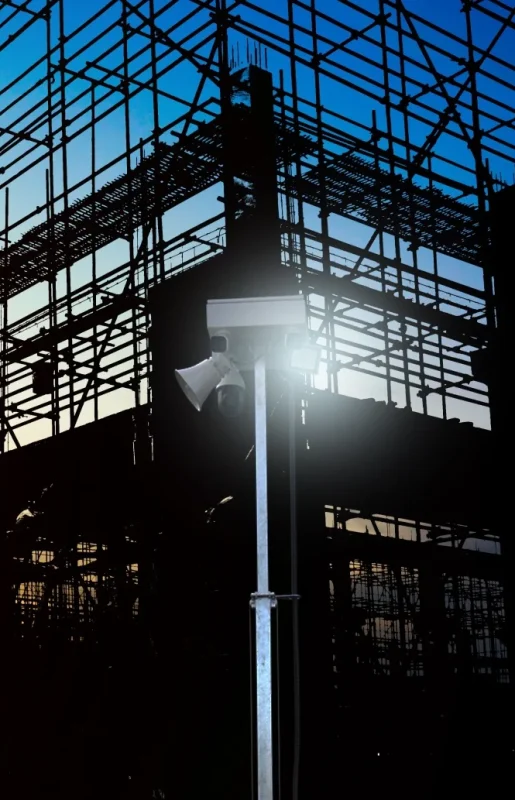ViSec Security Tower für Baustellenüberwachung, im Vordergrund ein Turm mit Kameras und dahinter ein Gerüst bei Sonnenuntergang.